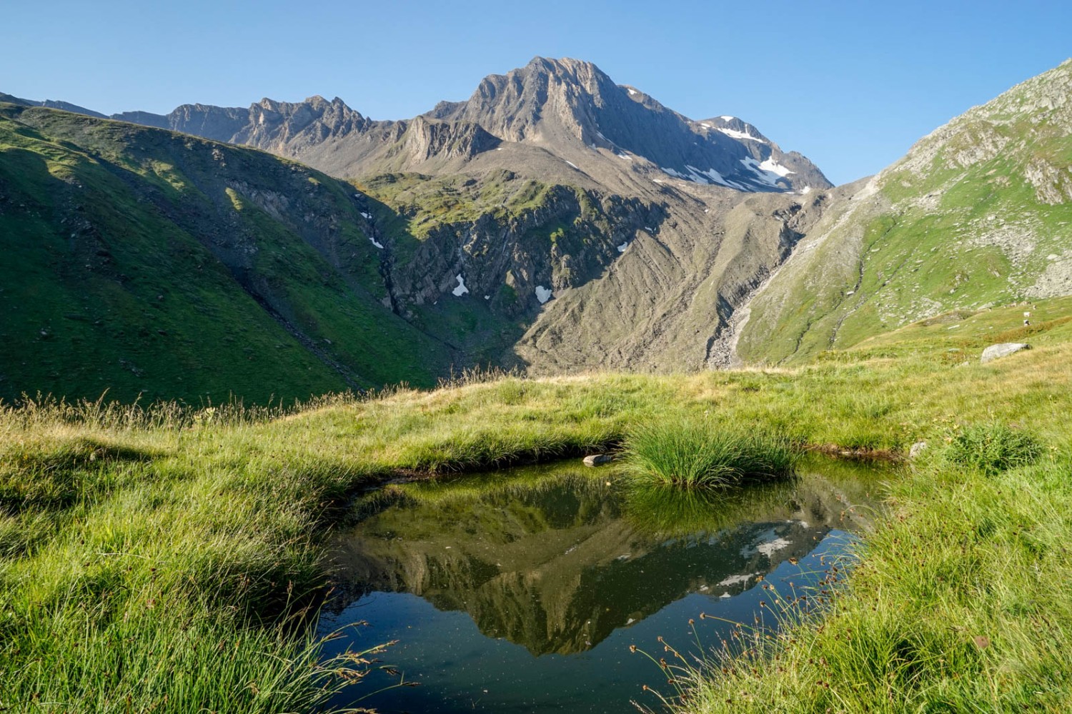 Die Ritzhörner spiegeln sich in einem Weiher im Lengtal. Bild: Fredy Joss